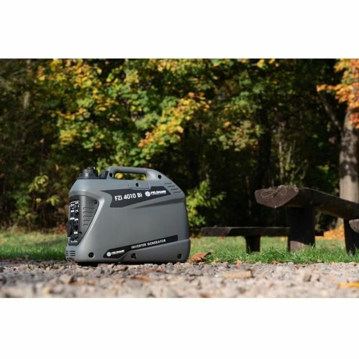 Fieldmann FZI 4010-Bi inverter aggregaat op grind in een parkachtige buitenomgeving met bomen op de achtergrond