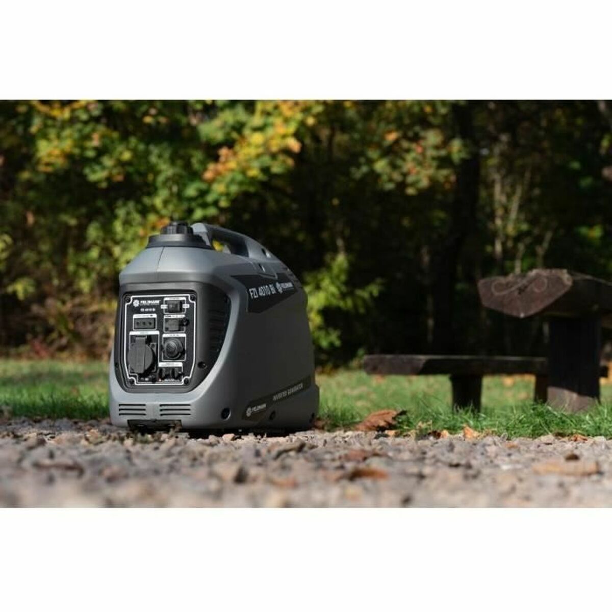Fieldmann FZI 4010-Bi inverter aggregaat op grind in een groene buitenomgeving met zichtbaar frontpaneel en bomen op de achtergrond